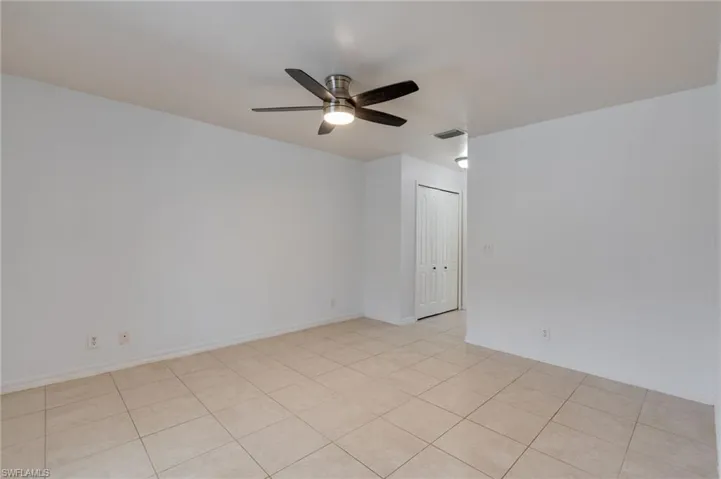 Spacious room featuring tile flooring, a ceiling fan with integrated lighting, and neutral wall tones