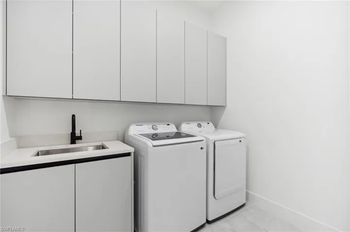 Laundry room with cabinets, washer and dryer, and sink