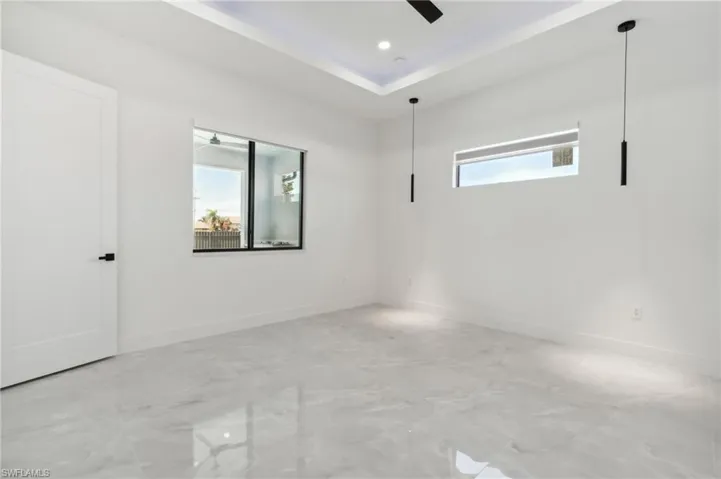 Unfurnished room featuring a raised ceiling and ceiling fan