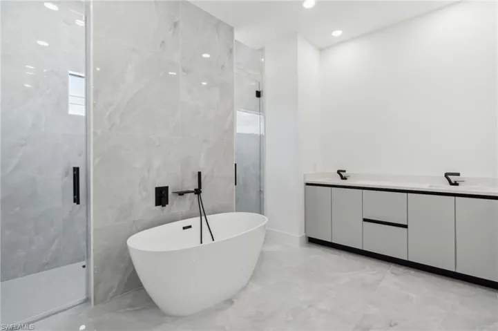 Bathroom with tile walls, independent shower and bath, and vanity