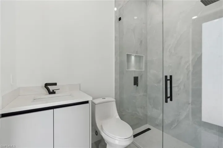 Bathroom featuring a shower with door, vanity, and toilet