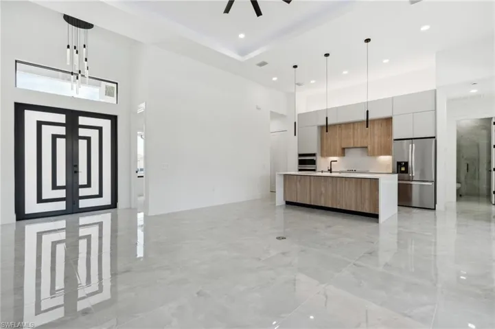 Kitchen with appliances with stainless steel finishes, decorative light fixtures, a high ceiling, and a large island