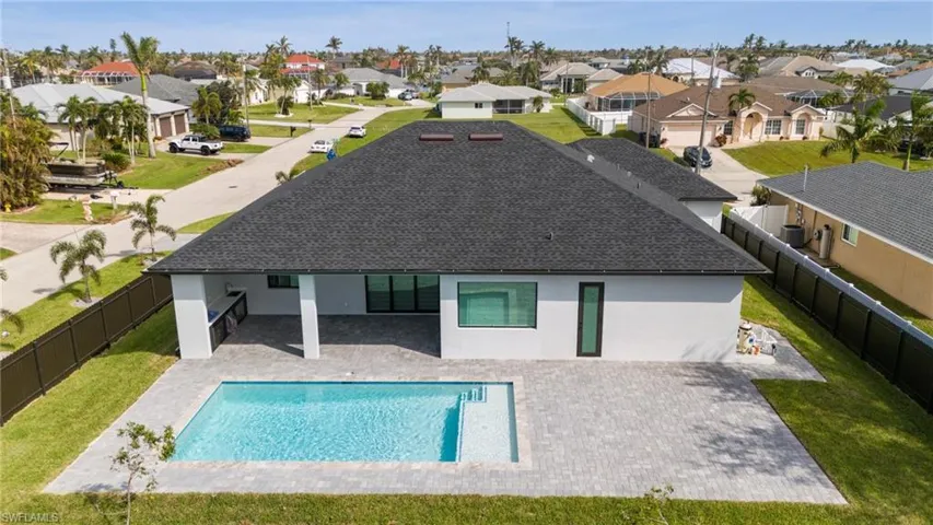 Rear view of property with a yard, a patio area, and a fenced in pool