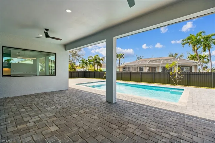 View of pool featuring a patio area, glass enclosure, and ceiling fan