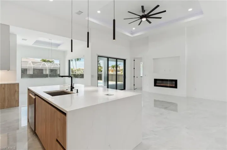 Kitchen featuring pendant lighting, sink, an island with sink, and a tray ceiling