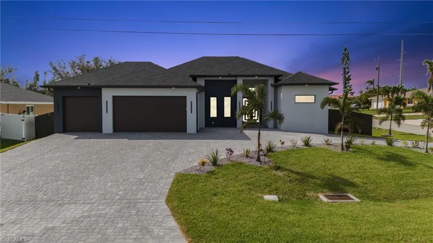 View of front of property featuring a lawn and a garage
