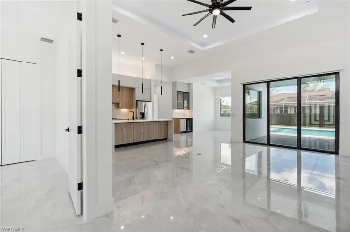Kitchen featuring stainless steel fridge with ice dispenser, ceiling fan, a tray ceiling, and pendant lighting
