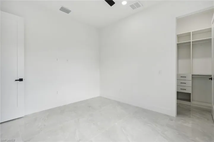 Unfurnished bedroom featuring a spacious closet, ceiling fan, and a closet