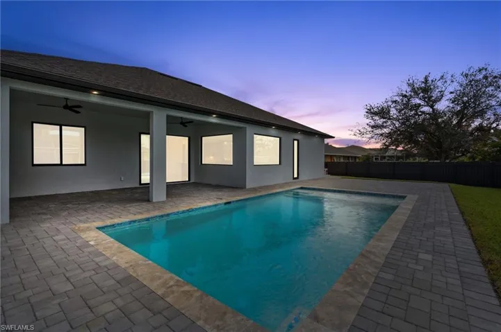 Pool at dusk with a patio and ceiling fan