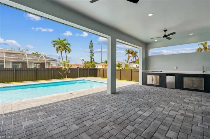 View of pool with a patio area, sink, a lanai, ceiling fan, and an outdoor kitchen