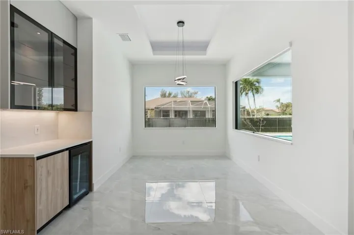Unfurnished dining area featuring beverage cooler, indoor bar, and a tray ceiling