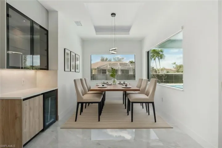 Dining room with a raised ceiling, indoor bar, and beverage cooler