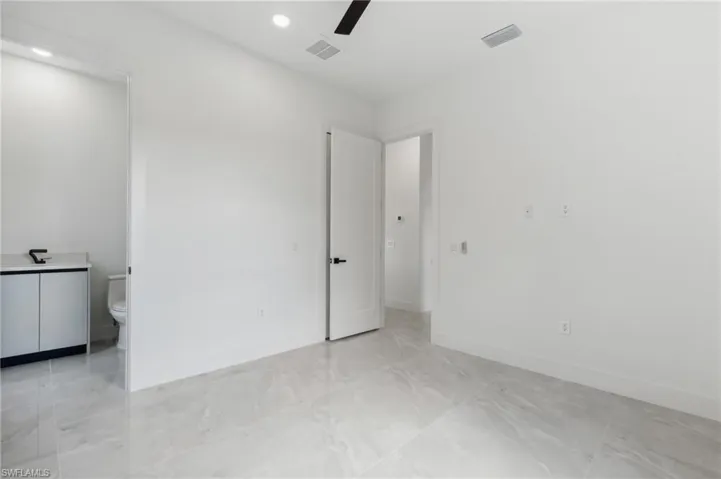 Unfurnished bedroom featuring connected bathroom and ceiling fan