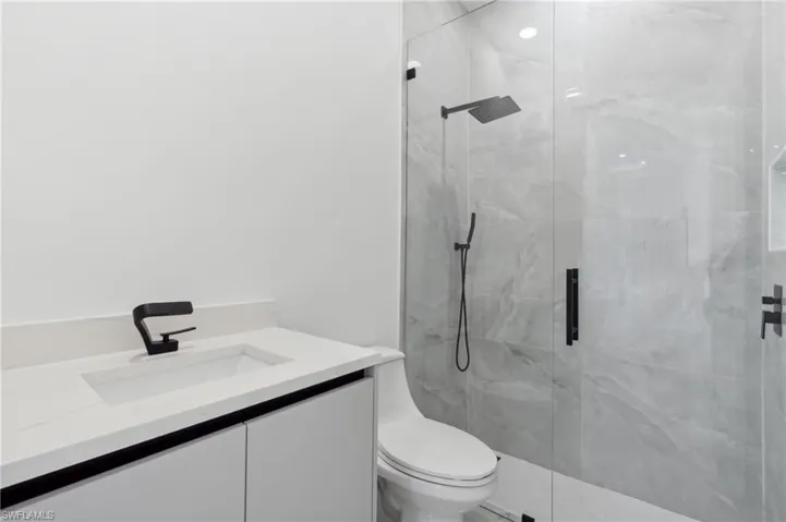 Bathroom featuring a shower with door, vanity, and toilet