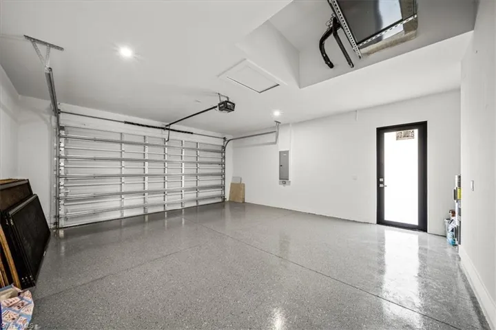 Garage featuring a garage door opener, electric panel, and recessed lighting