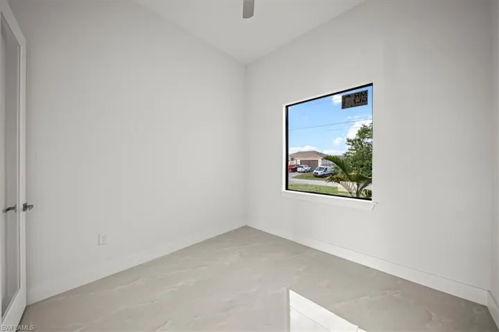 Empty room featuring baseboards, vaulted ceiling, ceiling fan, and light marble finish flooring