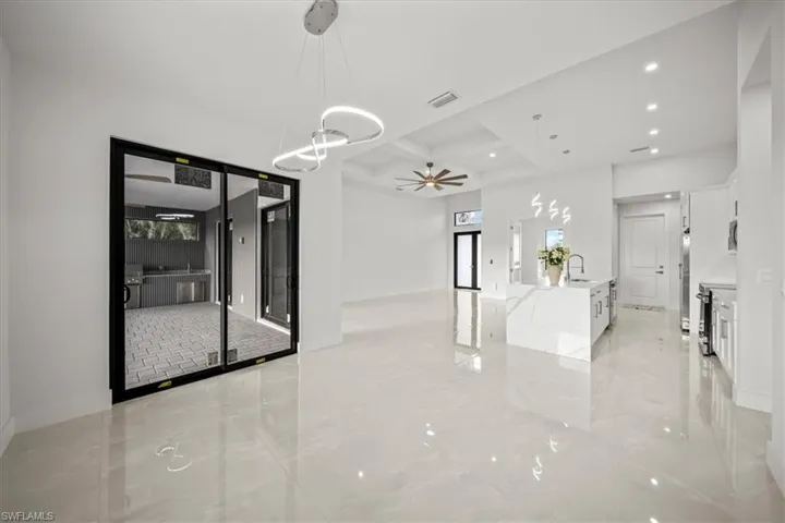 Spare room with coffered ceiling, a sink, light marble finish flooring, recessed lighting, and beam ceiling