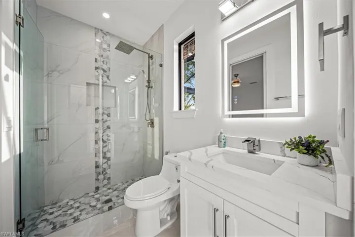 Full bath with vanity, a marble finish shower, toilet, recessed lighting, and marble finish floors