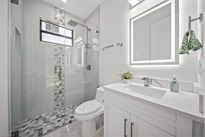 Bathroom featuring vanity, a marble finish shower, and toilet