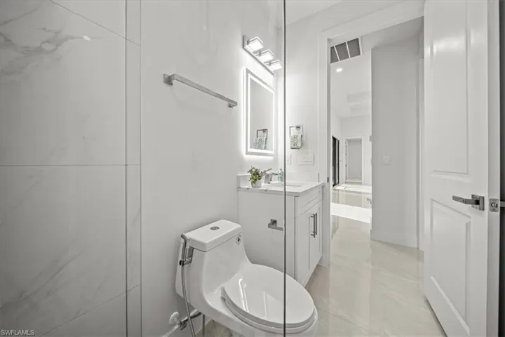 Full bathroom with marble finish flooring, vanity, and toilet