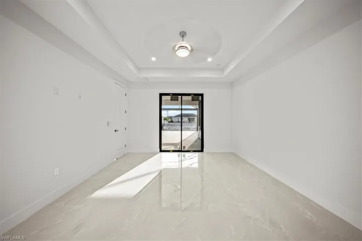 Unfurnished room featuring light marble finish flooring, baseboards, and a raised ceiling