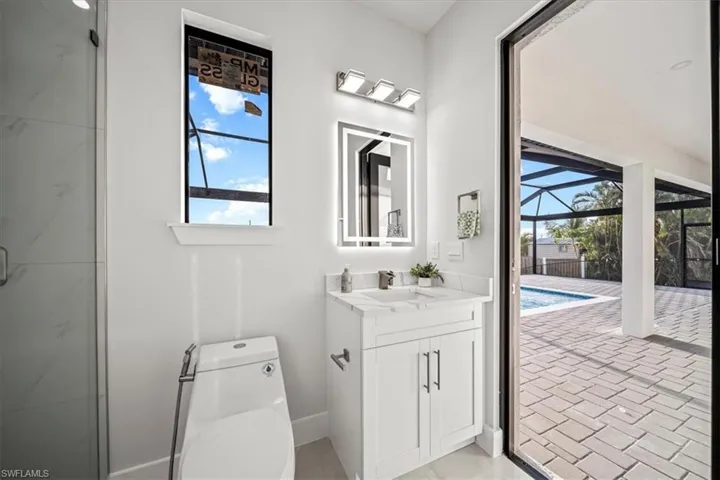 Bathroom featuring vanity, toilet, a marble finish shower, and brick patterned flooring