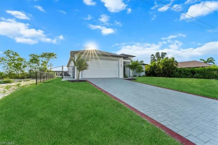 View of front facade with decorative driveway, a garage, a front lawn, and stucco siding