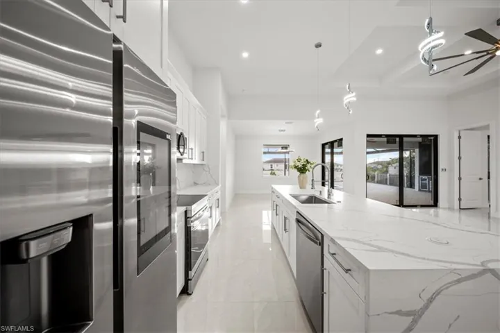 Kitchen with appliances with stainless steel finishes, a sink, recessed lighting, white cabinetry, and hanging light fixtures