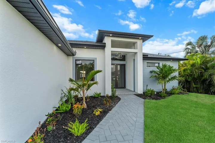 Doorway to property with stucco siding and a lawn
