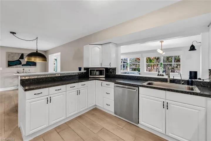 Kitchen featuring white cabinetry, stainless steel appliances, backsplash, light wood plank porcelain tile flooring
