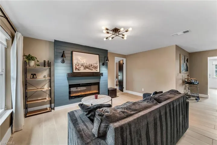 Family room  featuring light wood plank porcelain tile flooring and a fireplace