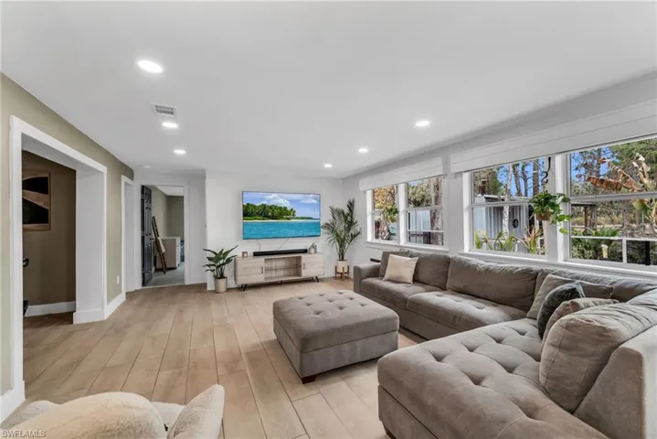 Living area featuring light wood plank porcelain tile flooring and recessed lighting