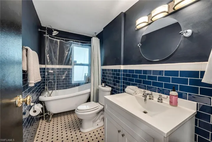 Bathroom featuring tile walls, vanity, a combined bath / shower claw foot freestanding tub