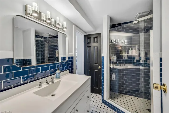 Full bathroom with a shower stall, vanity, backsplash, and tile walls