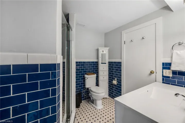 Bathroom featuring a stall shower, vanity, and tile walls