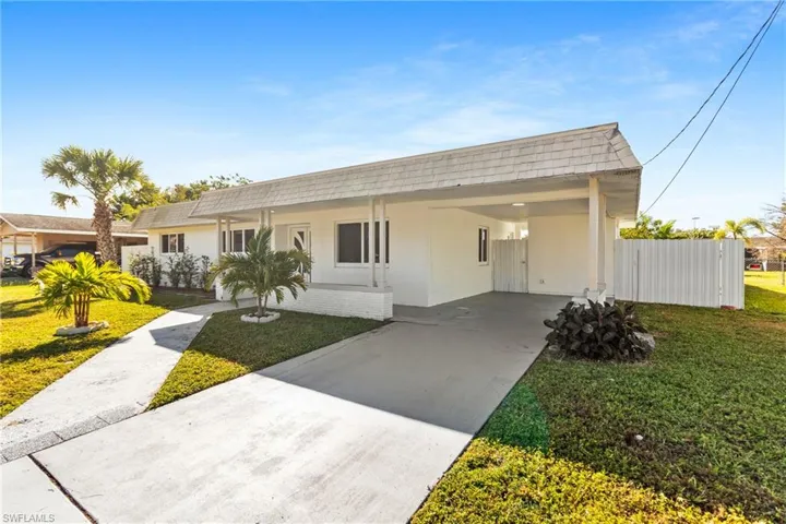 View of front of home featuring a front yard, stucco siding, a carport, and concrete driveway
