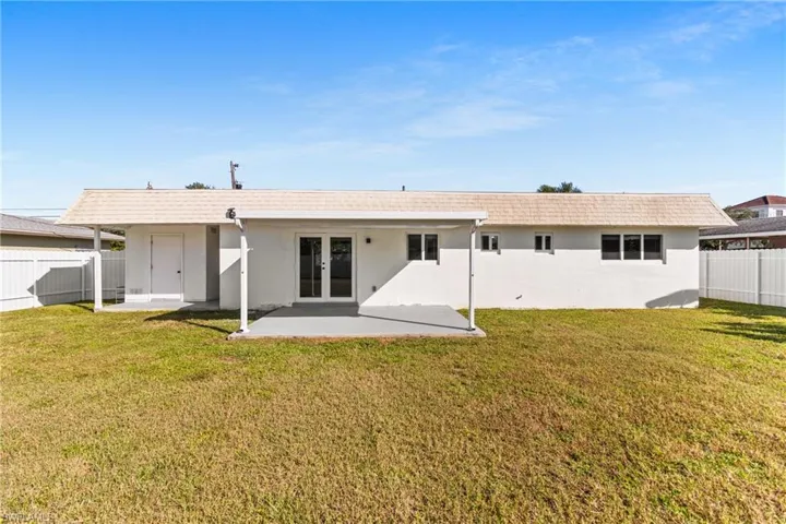 Back of property featuring a fenced backyard, stucco siding, french doors, a patio area, and roof with shingles