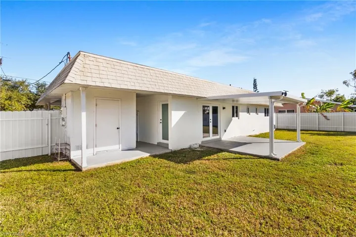 Back of house with stucco siding, a fenced backyard, a patio, french doors, and mansard roof