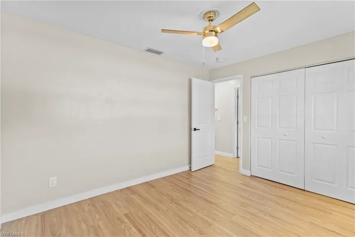 Unfurnished bedroom with light wood finished floors, a closet, and a ceiling fan
