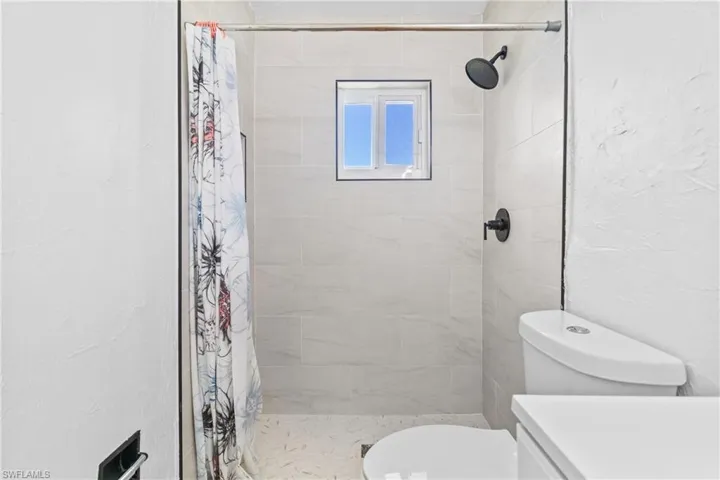 Bathroom with a textured wall, a shower stall, and vanity