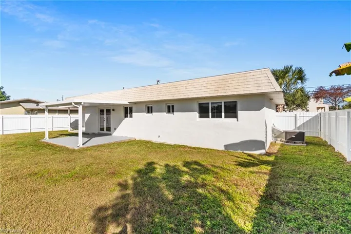Rear view of house with a fenced backyard, stucco siding, a patio, french doors, and roof with shingles