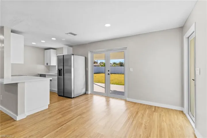 Kitchen featuring stainless steel refrigerator with ice dispenser, white cabinets, light wood-style flooring, recessed lighting, and french doors