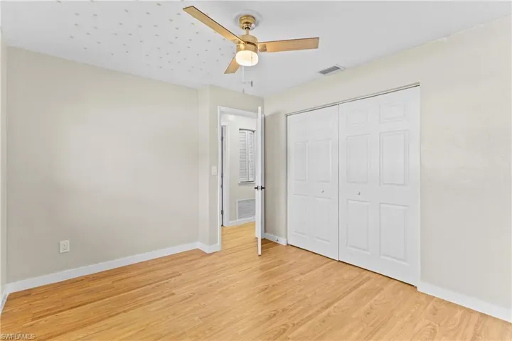 Unfurnished bedroom with light wood-type flooring, ceiling fan, and a closet