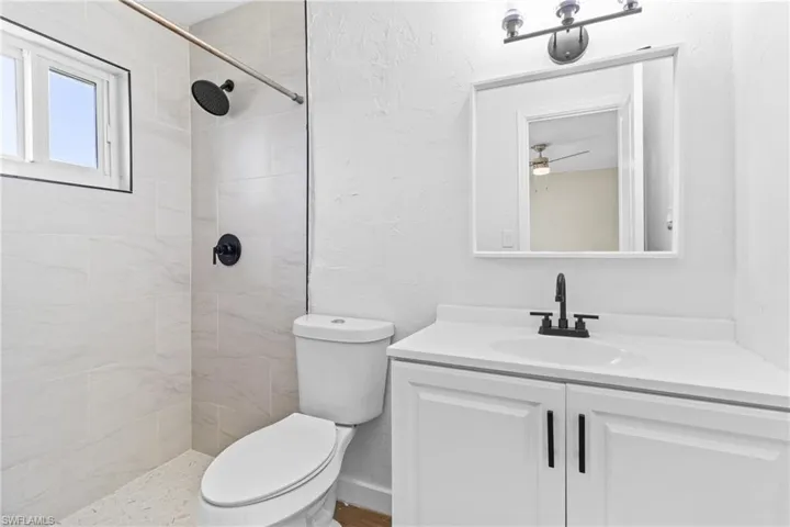 Full bath with a textured wall, a shower stall, and vanity