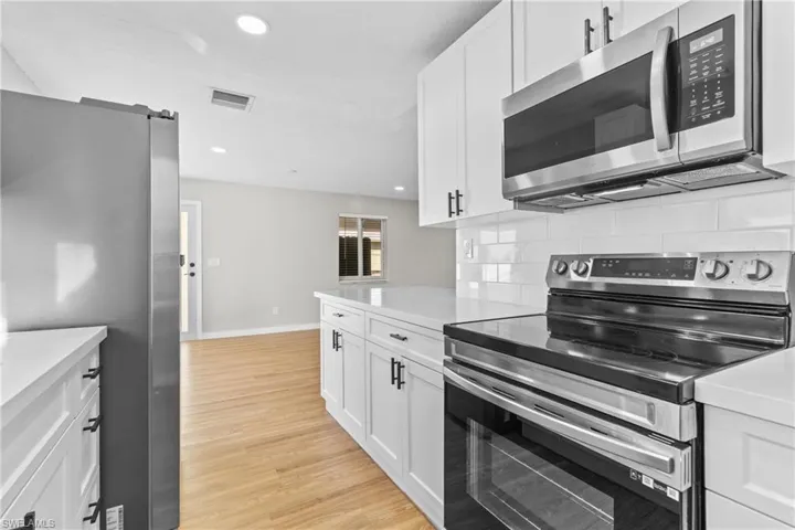 Kitchen with stainless steel appliances, white cabinetry, recessed lighting, tasteful backsplash, and light wood-style flooring