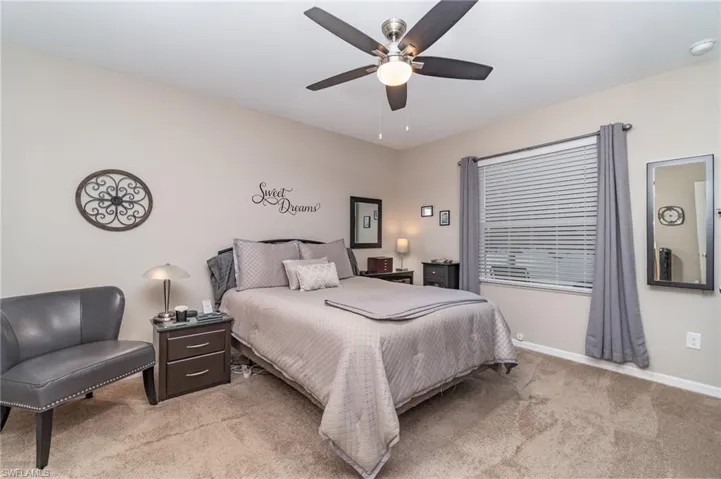 Primary Bedroom featuring 2 walk in closets, ceiling fan and light colored carpet