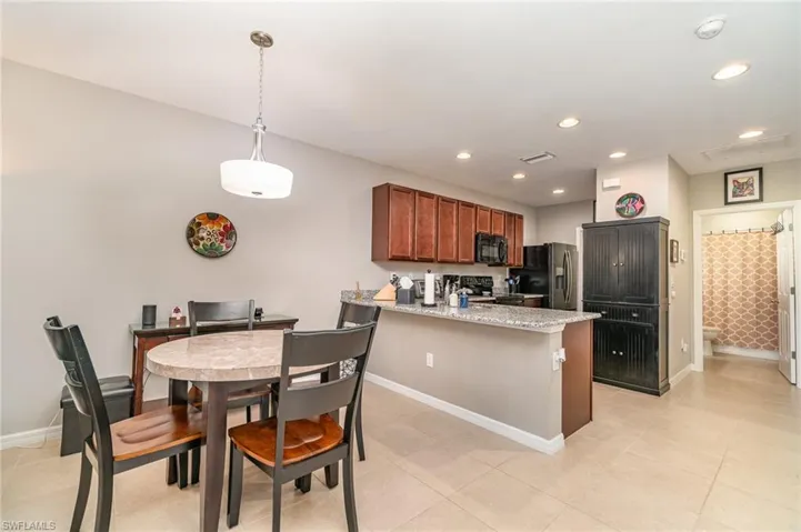 Kitchen featuring recessed lighting, black & stainless appliances, granite countertops, kitchen peninsula, and light tile patterned flooring