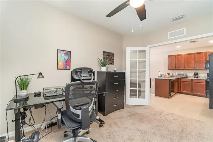 Den area with light colored carpet and ceiling fan