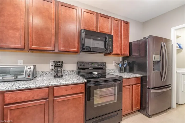 Kitchen with granite countertops with stove, microwave and fridge
