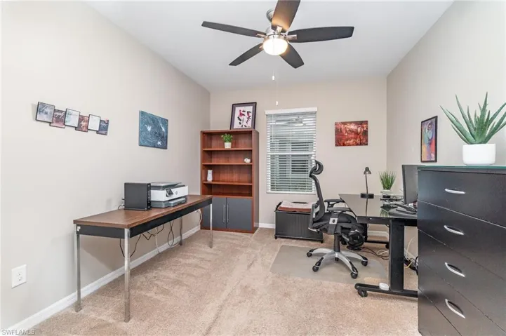 Carpeted den featuring ceiling fan